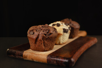 pastry chef presenting homemade vanilla and chocolate chips muffins  on a black background with sugar