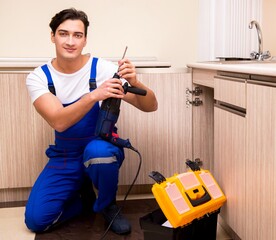 Young repairman working at the kitchen