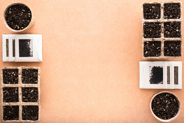 Biodegradable peat pots and trays with potting soil and seeds in small envelopes for sowing, on a raw surface with copy space, eco-friendly seed starter 