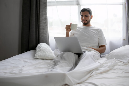 Hombre en videollamada acostado cómodamente en su cama