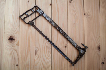 Old hacksaw for metal on a light wooden background. Work concept. - obrazy, fototapety, plakaty