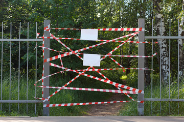 Barrier tape at the entrance to the city park, blank white sheets of paper for messages.