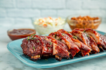 Sliced barbeque ribs on blue plate with side dishes
