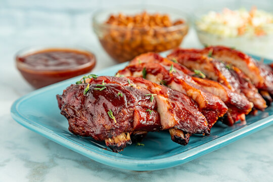 Sliced barbeque ribs on blue plate with side dishes