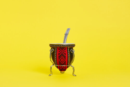 front view of argentine mate cup with straw on yellow background