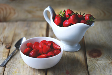 A bowl of chopped strawberries. Gravy boat with strawberries.