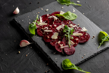 Young beet carpaccio with parmesan, nuts, arugula and garlic with olive oil. Vegan food.