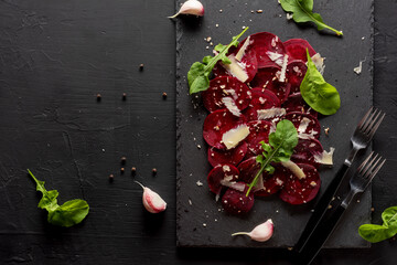 Young beet carpaccio with parmesan, nuts, arugula and garlic with olive oil. Vegan food.