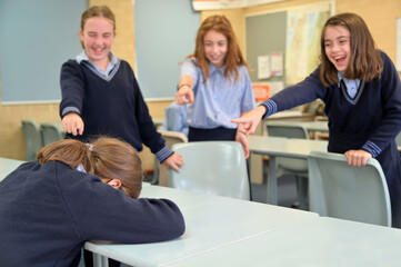 Mean schoolgirls bulling a schoolgirl in classroom