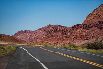 Fototapeta na wymiar Desert highway at sunset, travel concept, USA. Landscape with orange rocks, sky with clouds and asphalt road in summer. American roadtrip.