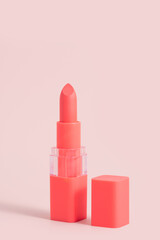 Pink lipstick tones coral with an open cap on a pink background. Lip cosmetics concept. Summer bright colors for lips.