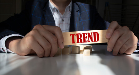 Businessman hand holding wooden cube block with TREND business word on table background. Mission, Vision and core values concept