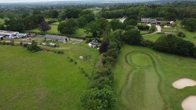 static drone shot showing a hedge row between two golf courses in the middle of the english countryside