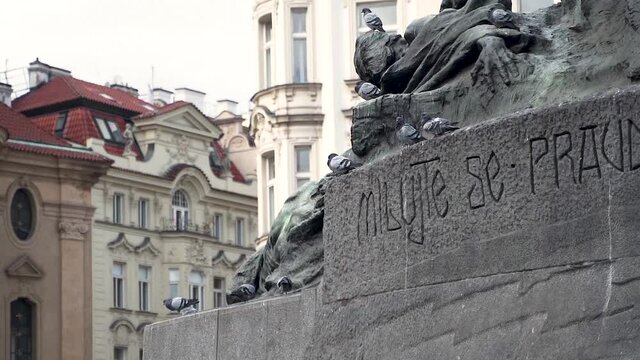 Flock of pigeons sitting on a stone statue monument in Prague city.