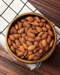 Top view of almonds in wooden bowl on the table, Flat lay, Healthy snack, Vegetarian food.