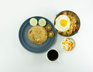 Fried rice served with fresh tomatoes and meatballs in a green tosca ceramic plate and pickles on a white bowl on a white background