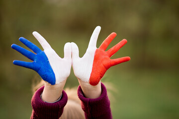 Freedom France concept. Cute child forming flying bird gesture with painted in France colors hands...