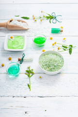 beauty product samples with chamomile flowers on white wooden table