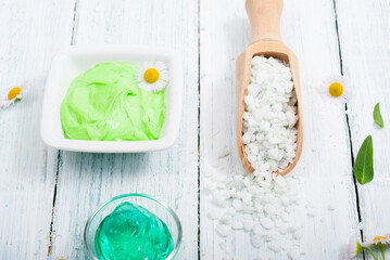 beauty product samples with chamomile flowers on white wooden table
