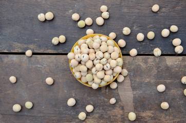 closeup bunch the ripe yellow brown peas beans in the plastic bowl over out of focus wooden brown background.