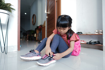 cute primary student put her shoes on. preparing to go to school in the morning