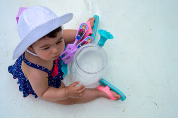 cute little girl playing in swimming pool at beach