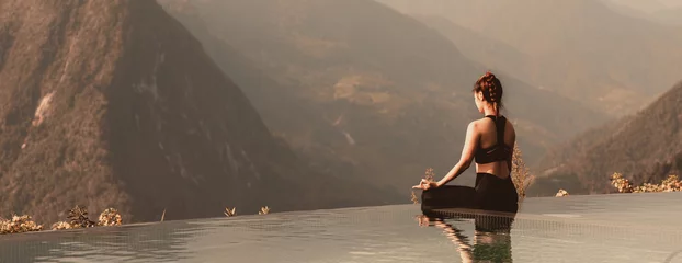 Schilderijen op glas Banner Calm of Athletic Asian woman practice yoga Lotus pose on the pool in the morning in front of beautiful nature views,Healthy woman breathing and meditation yoga comfortable and relax,Warm tone © 220 Selfmade studio