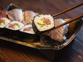 鯵の巻き寿司のクローズアップ。プラスチック容器に入った鯵の握り寿司と巻き寿司。