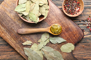 Spoon with tasty pesto sauce on wooden background