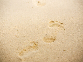 Fototapeta na wymiar Beach sand footprints with copy space. Close up human footprint from walking barefoot on the sand beach background. Journey, summer background concept.