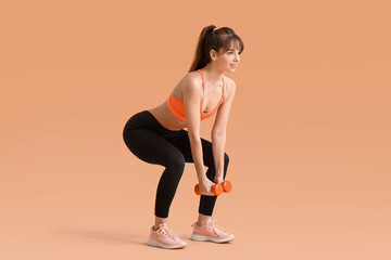 Fototapeta na wymiar Sporty young woman training with dumbbells on color background