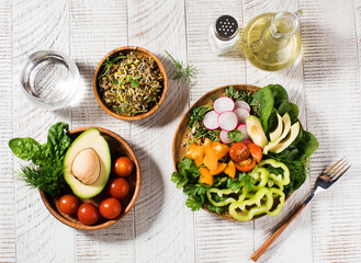 Vegetable summer salad with avocado, seasonal vegetables, spinach and micro-greens on a wooden white background. 