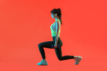 Fototapeta na wymiar Sporty young woman training with dumbbells on color background