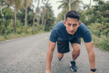 Athlete man in running start pose on the road in the forest. Start and goal concept.