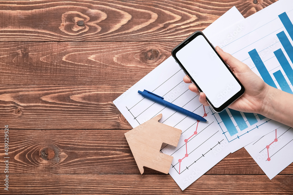 Wall mural Woman with mobile phone and charts on wooden background