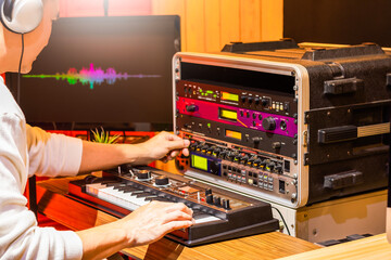 male professional musician playing synthesizer keyboard while editing tone on effect processor...