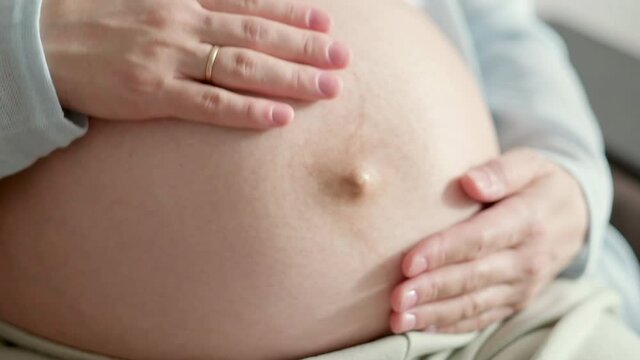 4k Pregnant expectant mother caressing her belly. Woman hands touching her tummy, waiting child. Preparation for childbirth, Girl big belly advanced pregnancy