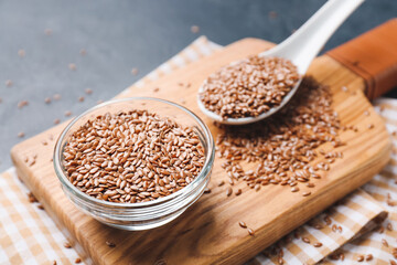 Composition with bowl and spoon of flax seeds on color background, closeup