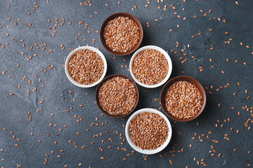Composition with bowls of flax seeds on dark background