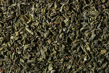 Dry green tea leaves as background, closeup