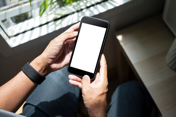 Close up view man sitting near window and using smart phone.