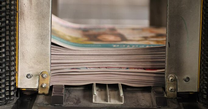 Newspaper production - Machine sorting daily papers in to stacks before being sent to binding machine.