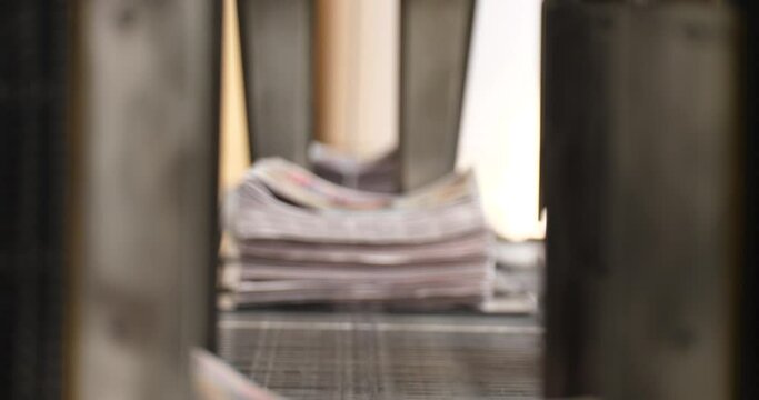 A worker in a Newspaper printing press loads papers by hand on to the binding machine