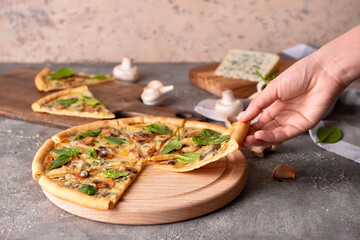 Female hand taking slice of tasty pizza on grunge background
