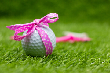 Golf ball with pink ribbon for Breast Cancer Awareness concept on green grass