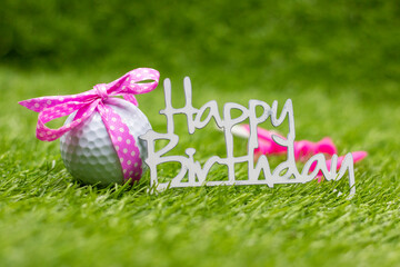 Golf ball with Happy Birthday sign are on green grass