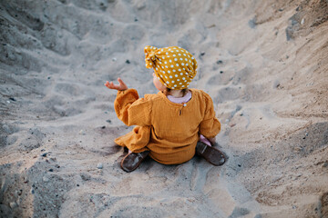 Funny child in oriental dress sitting on beach sand