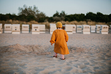 Little child walking on sunset beach on baltic sea among baskets