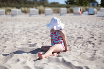 Little girl on white sand beach enjoying summer, sun and vacation