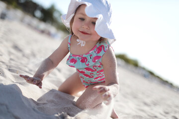 Little happy girl crawling on white sand beach enjoying summer, vacation